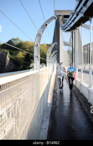 A fine sunny morning on Bristol`s famous Clifton suspension bridge with two female joggers crossing it. Stock Photo
